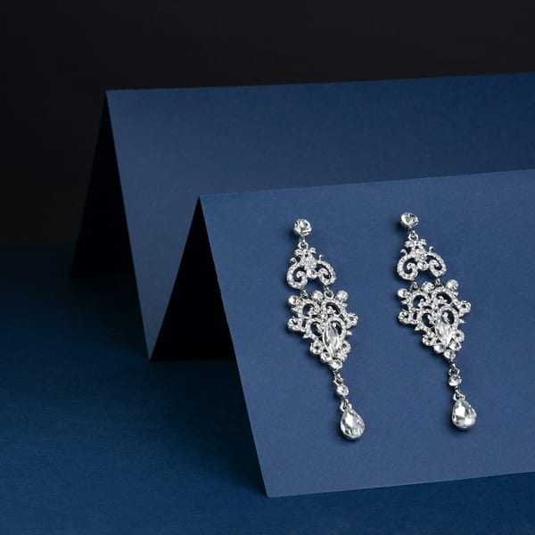 Long white gold chandelier earrings set with diamonds, on a blue card