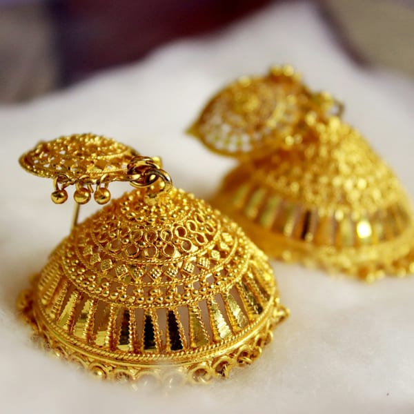 Pair of large gold filigree dome jhumkas on white cloth