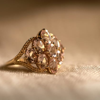 Rose gold cocktail ring with a flower-shaped cluster of stones, on cream cloth