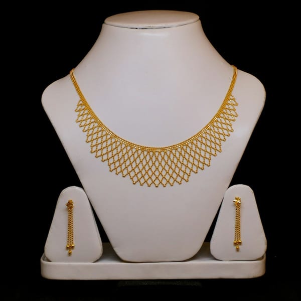 Gold mesh bib necklace with long drop earrings on a cream bust