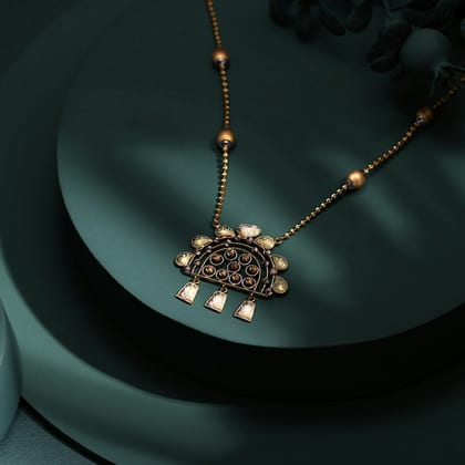 Fine gold necklace with a small fan-shaped pendant on a dark green stand