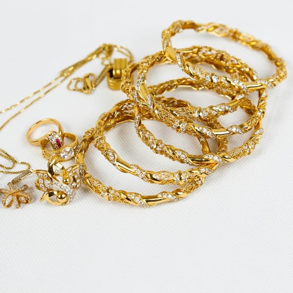 A pile of slim twisted gold bangles on white