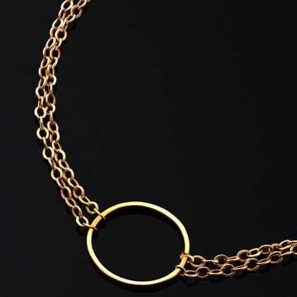 Fine gold chain with an open circle at its centre, on black