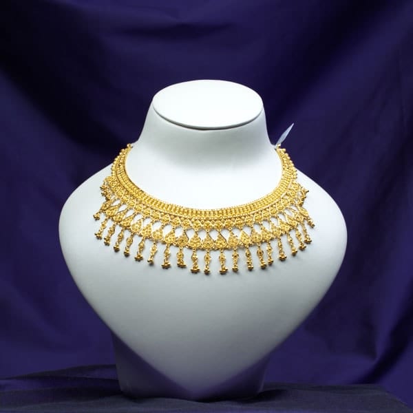 Antique-finish 22K gold bib necklace edged with pearl drops on a white bust