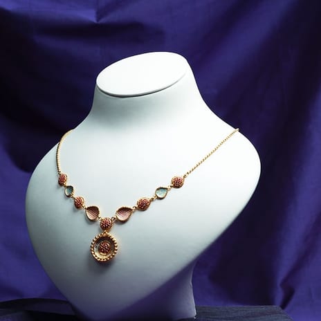 22K gold necklace set with rubies and emeralds on a white bust
