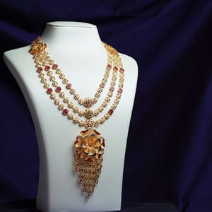 Three-strand 22K gold rani haar with a flower pendant and a long fringe on a white bust
