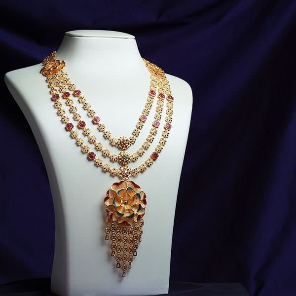 Three-strand 22K gold rani haar with a flower pendant and a long fringe on a white bust