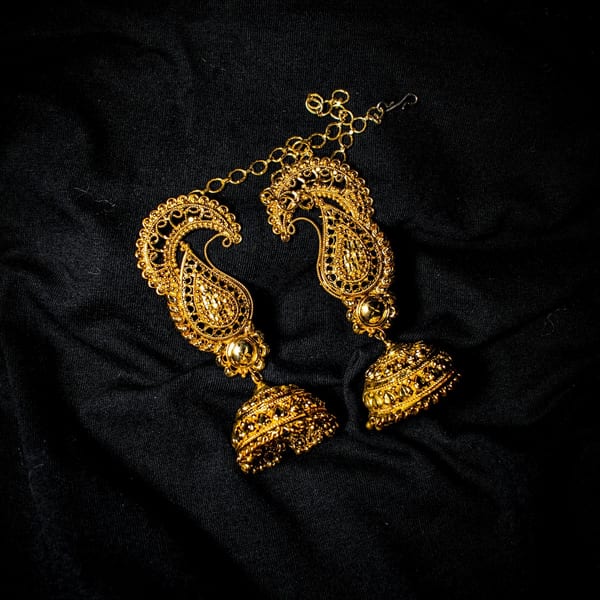 Gold paisley earrings with bell-shaped jhumka drops on black silk