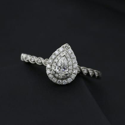 White gold ring with a pear-cut diamond in a halo, on black