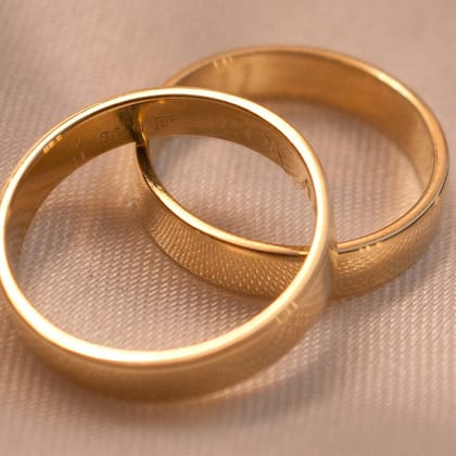 Two interlocking plain gold wedding bands on cream fabric