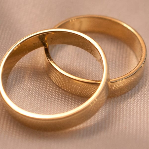 Two interlocking plain gold wedding bands on cream fabric