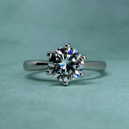 White gold solitaire ring with a round diamond in six claws, on teal