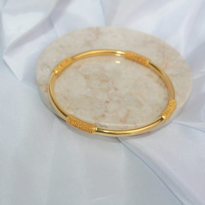 One slim gold bangle on a marble dish