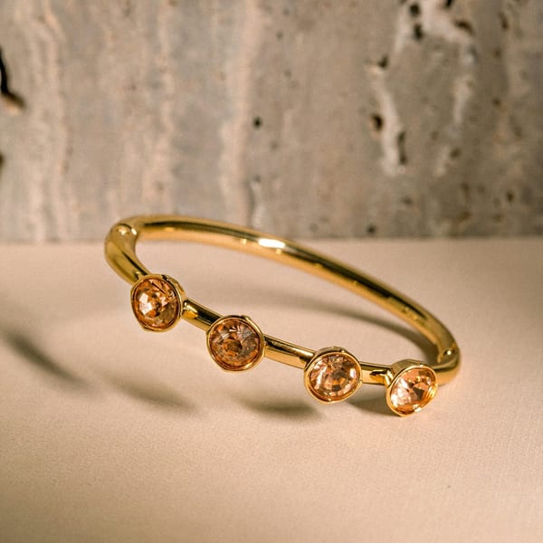 Slim rose gold open cuff with three round stones, on stone
